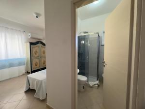 a bathroom with a toilet and a bed and a shower at Garden Hotel Alghero in Fertilia