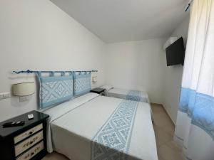 a small bedroom with a bed and a dresser at Garden Hotel Alghero in Fertilia