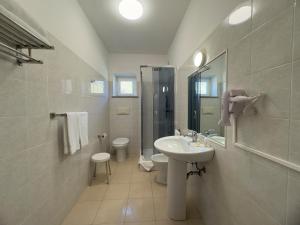 a white bathroom with a sink and a toilet at Garden Hotel Alghero in Fertilia