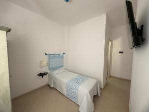 a white room with a bed and a television at Garden Hotel Alghero in Fertilia