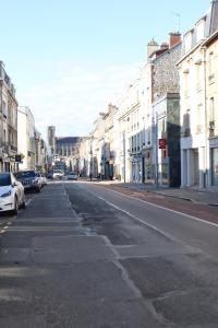 an empty city street with parked cars and buildings at Pauline's Home Gambetta in Reims