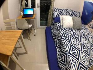 a room with a bed and a desk with a laptop at The Grass Residences in Manila