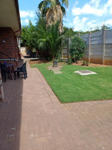 a patio with a lawn with chairs and a fence at Cura Lodge in Bloemfontein