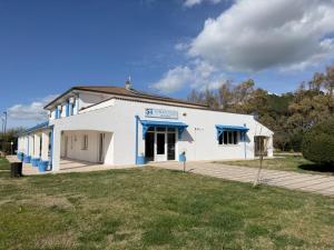 a white building with blue windows and a yard at Garden Hotel Alghero in Fertilia