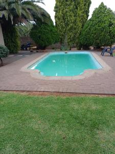 a swimming pool in a yard with a brick at Cura Lodge in Bloemfontein