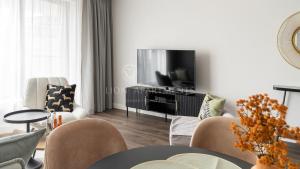 a living room with a tv and a table and chairs at Lion Apartments - SCALA City Center Apartments&Parking IA in Gdańsk