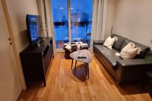 een woonkamer met een bank en een televisie bij Relax in a cozy studio overlooking downtown in Tromsø