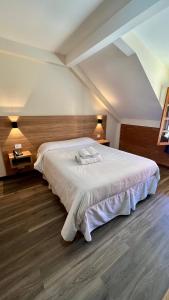 um quarto com uma grande cama branca num quarto em Hotel Garnier em Campos do Jordão