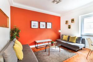 リスボンにあるTelhal by Central Hill Apartmentsのオレンジ色のアクセントの壁のリビングルーム