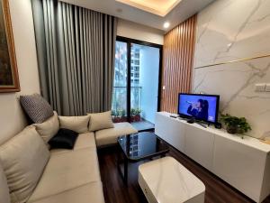 sala de estar con sofá blanco y TV en Na Mit HomeStay, en Hai Phong