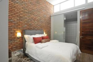 a bedroom with a white bed and a brick wall at Serviced apartments in Eros in Windhoek