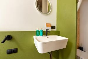 a bathroom with a white sink and a green wall at Au Chat Qui Dort Lille - Magasin in Lille