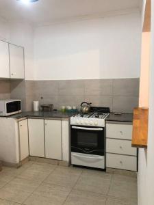 Il comprend une cuisine équipée d'une cuisinière et de placards blancs. dans l'établissement Amplio y luminoso apartamento., à Buenos Aires