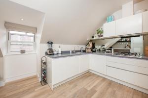 una cucina con armadietti bianchi e pavimenti in legno di Luxury 2 Bed Apartment - 28 mins train to London a Addlestone