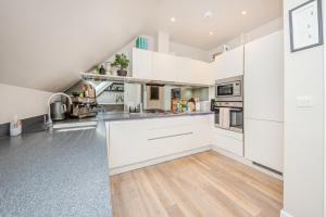 una cucina con armadietti bianchi e pavimenti in legno massello di Luxury 2 Bed Apartment - 28 mins train to London a Addlestone