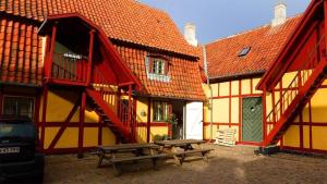 ein gelbes und rotes Gebäude mit einem Tisch und Bänken in der Unterkunft Købmandsgaarden Kerteminde in Kerteminde
