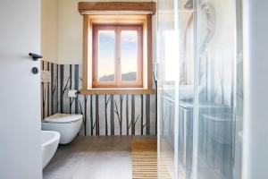 Un baño con inodoro y ventana. en Bellagio - Baita treeb Tivano, en Bellagio 33 fotos más