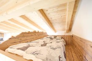 Ce lit se trouve dans un dortoir doté d'un plafond en bois. dans l'établissement Bellagio - Baita treeb Breva, à Bellagio