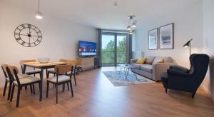 ein Wohnzimmer mit einem Sofa, einem Tisch und Stühlen in der Unterkunft Apartament Premium PINEA 413 in Pobierowo