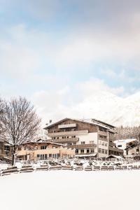 ein großes Gebäude mit schneebedeckten Bergen im Hintergrund in der Unterkunft Vital Hotel Ortlerspitz in Sankt Valentin auf der Haide