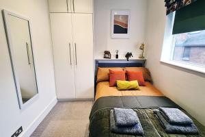 a small bedroom with a bed with orange pillows at Central London 1 bedroom flat in Kensington in London