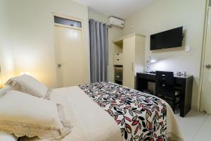 Schlafzimmer mit einem Bett, einem Schreibtisch und einem TV in der Unterkunft El Principe Hoteles in Piura