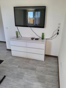 Una cómoda blanca con un televisor en la pared. en Adorable appartement, en Pézenas