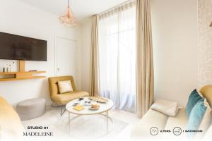 uma sala de estar branca com uma mesa e uma cadeira em Beauquartier - Madeleine em Paris