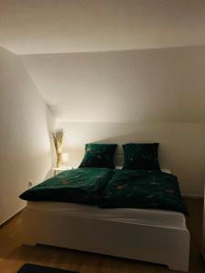 a bed with a green comforter in a room at Ferienwohnung Nannerl in Bad Sachsa