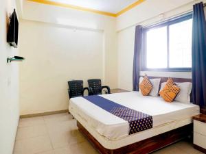 Un dormitorio con una cama con sillas y una ventana en SPOT ON Hotel Gaurav Lodge, en Pune
