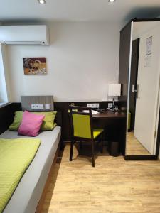 Zimmer mit einem Bett und einem Schreibtisch mit einem Tisch in der Unterkunft Hotel Gästehaus Stock Zimmer Schokotöpfle in Friedrichshafen