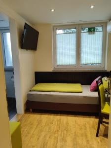 Bett in einem Zimmer mit 2 Fenstern und einem TV in der Unterkunft Hotel Gästehaus Stock Zimmer Schokotöpfle in Friedrichshafen