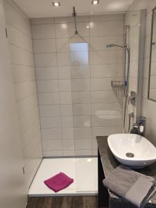 a bathroom with a glass shower and a sink at Hotel Gästehaus Stock Zimmer Schokotöpfle in Friedrichshafen