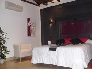 1 dormitorio con 1 cama blanca y 1 silla en Casa Rural con Jacuzzi La Dulce, en Cabañas de Polendos