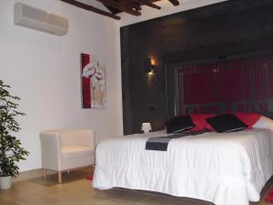 a bedroom with a white bed and a chair at Casa Rural con Jacuzzi La Dulce in Cabañas de Polendos