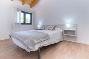 a white bedroom with a bed and a window at Casa rural de lujo en Alt Urgell, Pirineos. in Aravell