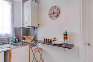 a kitchen with a counter and a clock on the wall at Appartement cosy au calme, proche de Paris et du RER B in Gentilly