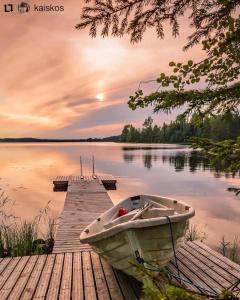 un bateau assis sur un quai à côté d'un lac dans l'établissement Beautiful and spacious lakeside cottages, à Imatra