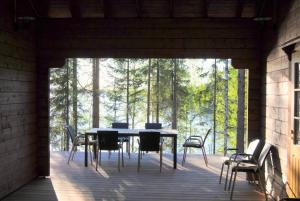 a table and chairs on a deck with a view of trees at Beautiful and spacious lakeside cottages in Imatra
