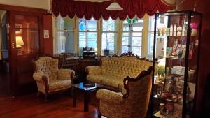 een woonkamer met 2 stoelen en een boekenplank bij KUBBA ROONGA GUESTHOUSE - Boutique Luxury Peaceful Stay & Gardens - Bed & Breakfast in Blackheath