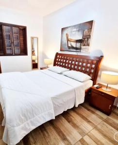 1 dormitorio con 1 cama grande con sábanas blancas en Estalagem 11 Suites, en Arraial do Cabo
