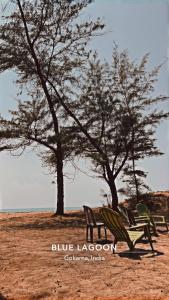 dos bancos de parque y dos árboles en un campo en Blue Lagoon Redefined, en Gokarna