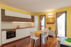 a kitchen with white cabinets and a table and chairs at Xenia Apartments - Cozy studio 10 min from Linate in Milan