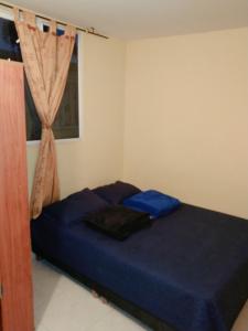 a bedroom with a blue bed with a window at Apartamento a 20 minutos del aeropuerto in Bogotá