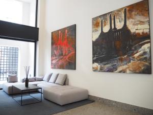 Washington Building - 4 posti في ميلانو: غرفة معيشة مع أريكة ولوحات على الحائط