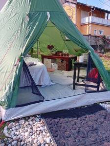 a green tent with a bed and a table at Indian tent glamping in Mrše