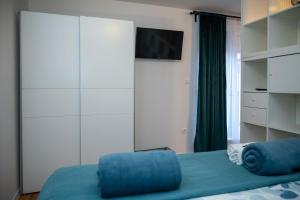 a bedroom with a bed with a blue pillow and a tv at Studio apartman Daruvar in Daruvar