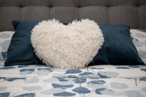 a white heart pillow sitting on top of a bed at Studio apartman Daruvar in Daruvar