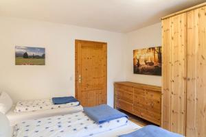 1 dormitorio con 2 camas y armario de madera en Ferienwohnung Mair - Sonnaufgang, en Halblech