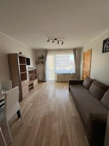 ein Wohnzimmer mit einem Sofa und Holzboden in der Unterkunft Baltic Apartament in Liepāja
